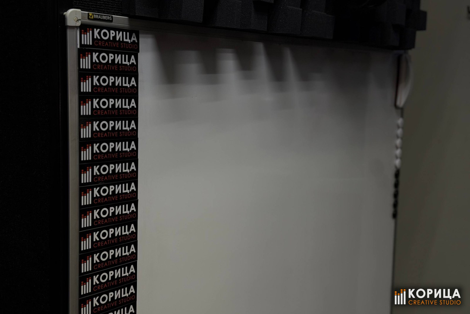 Стена-баннер с повторяющимся логотипом студии «Корица» — фон для съёмки в помещении