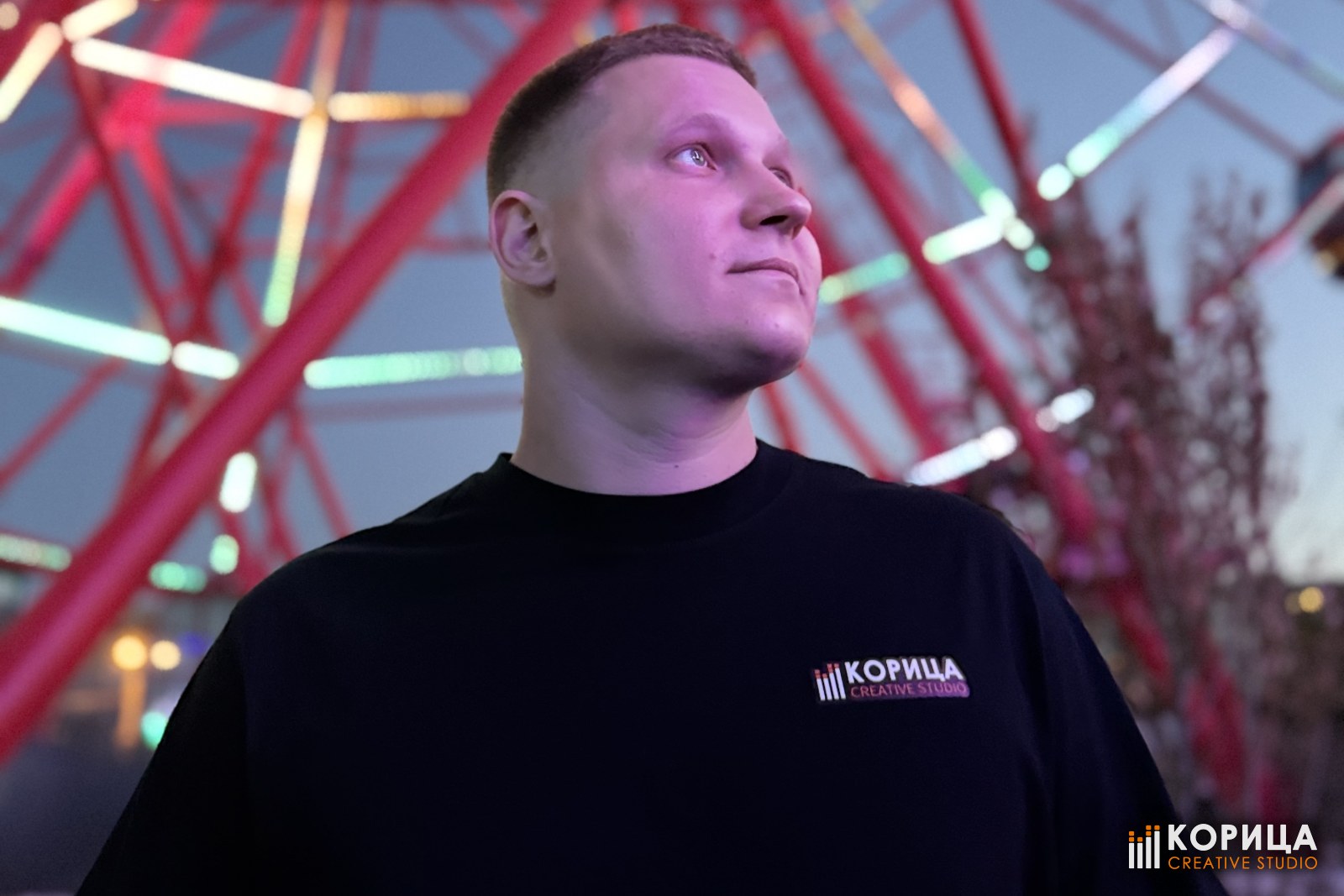 Представитель студии «Корица» в фирменной футболке на площадке под колесом обозрения
